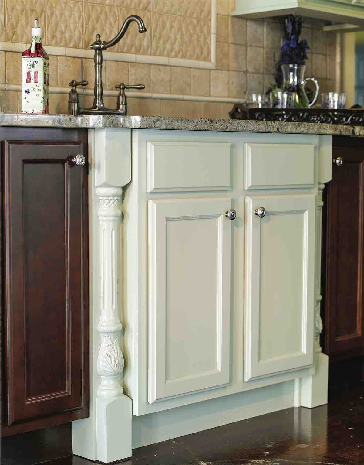 A kitchen with white cabinets and brown cabinets and a sink