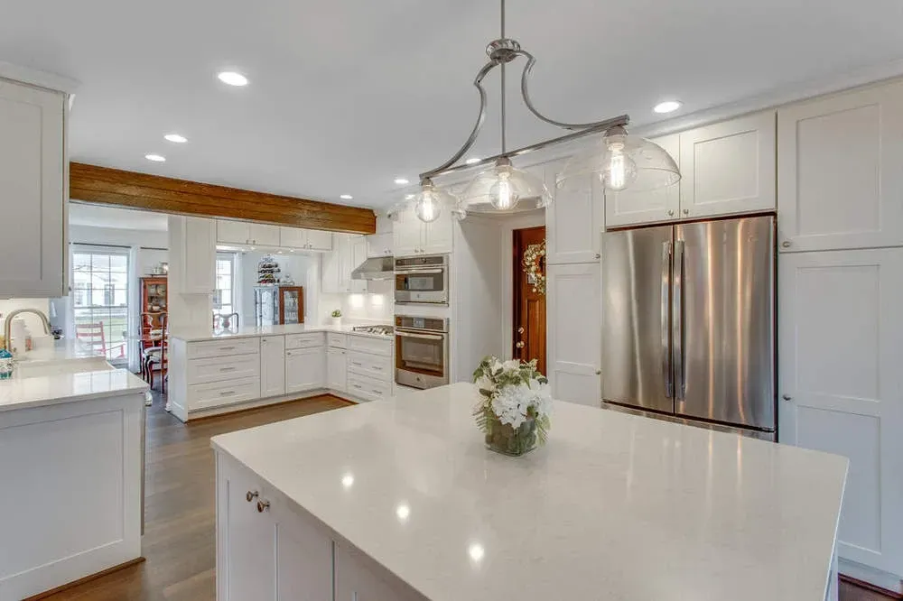 A kitchen with white cabinets , stainless steel appliances , and a large island.
