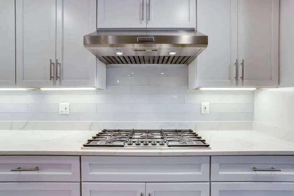 A kitchen with white cabinets and a stove top oven.