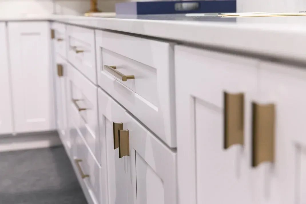 A kitchen with white cabinets and gold handles.