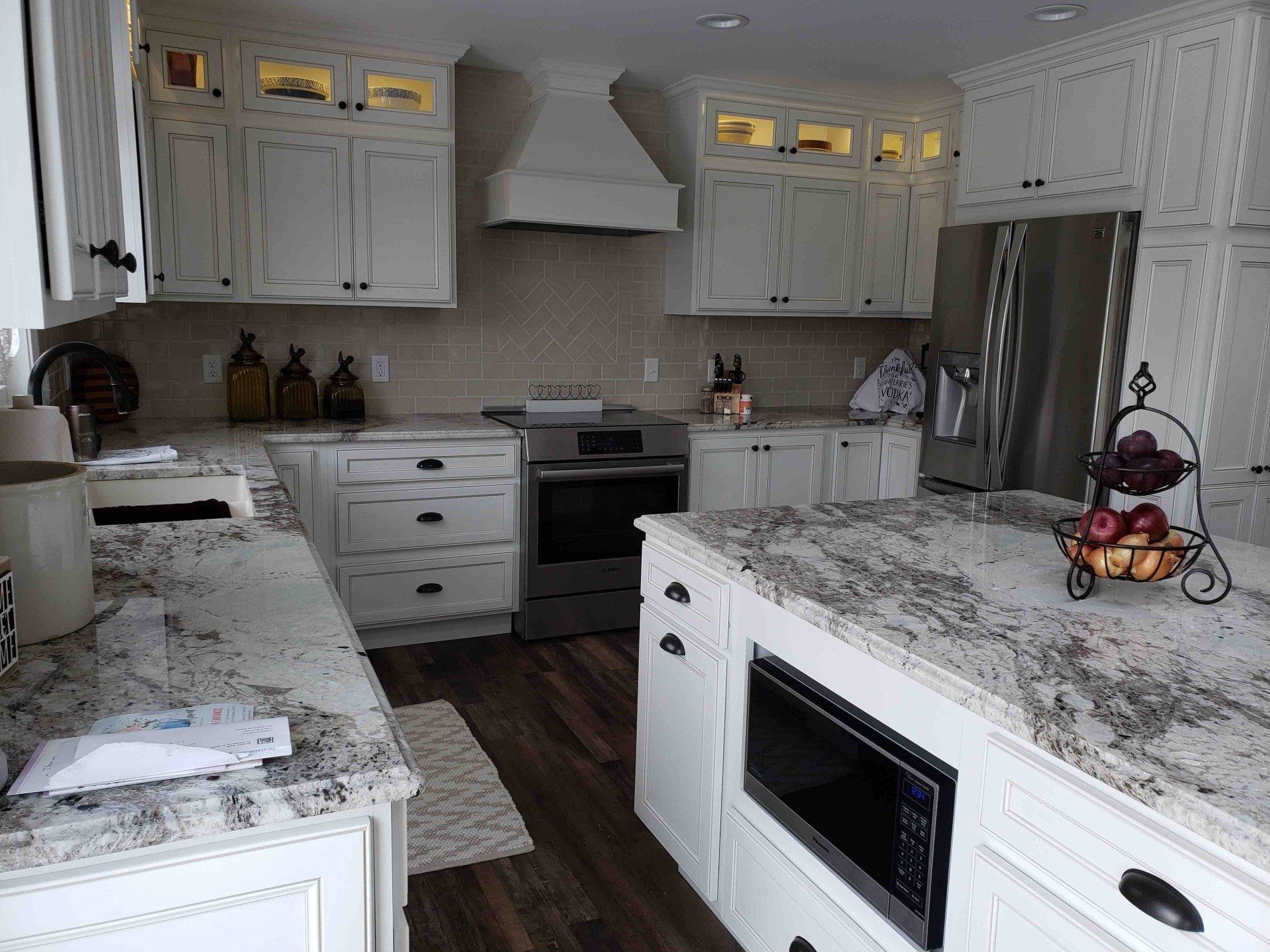 A kitchen with white cabinets and granite counter tops.