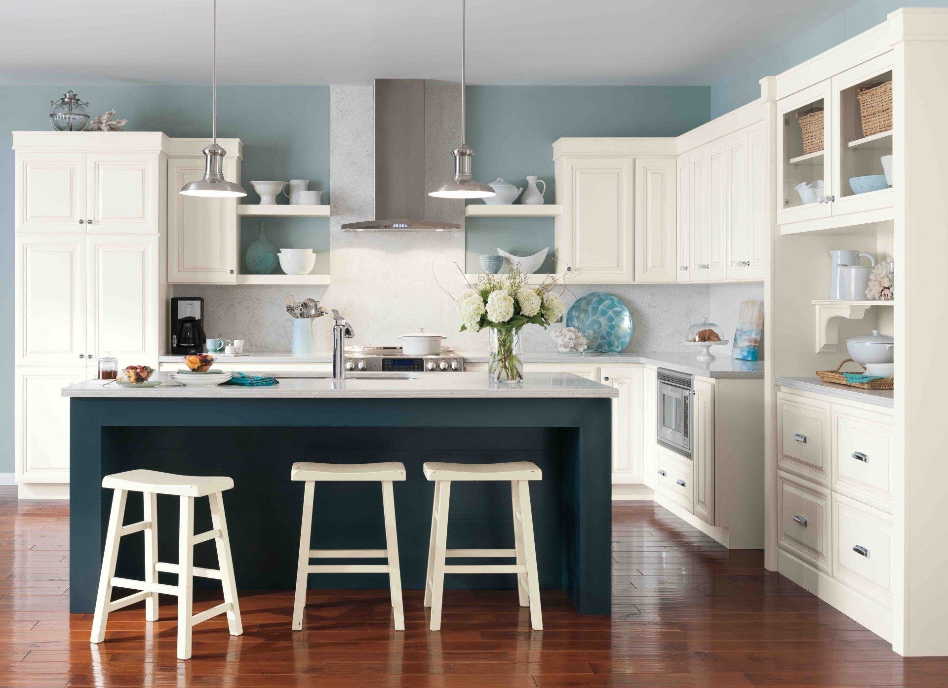 A kitchen with white cabinets and a blue island with stools