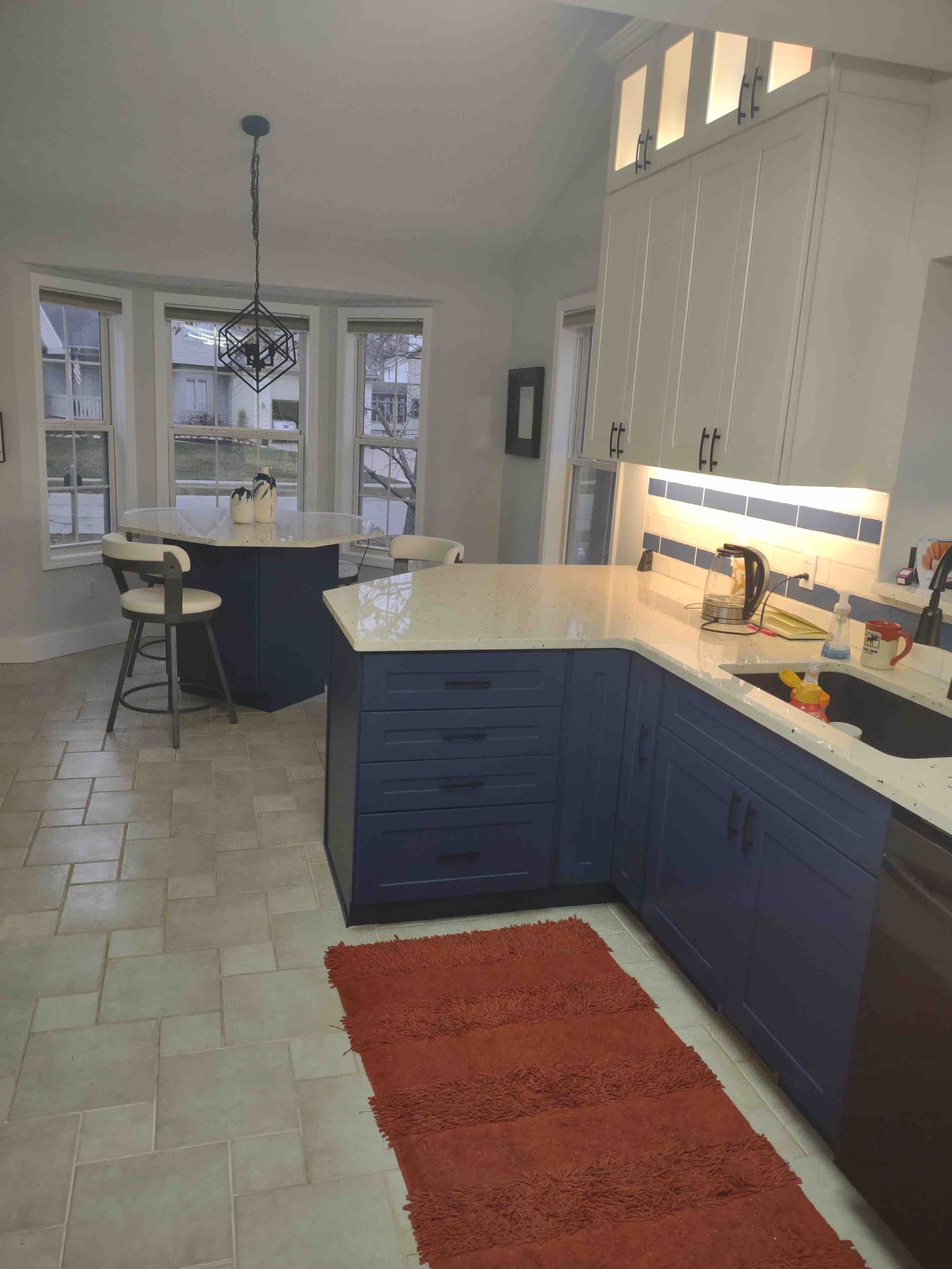 A kitchen with blue cabinets and a red rug on the floor