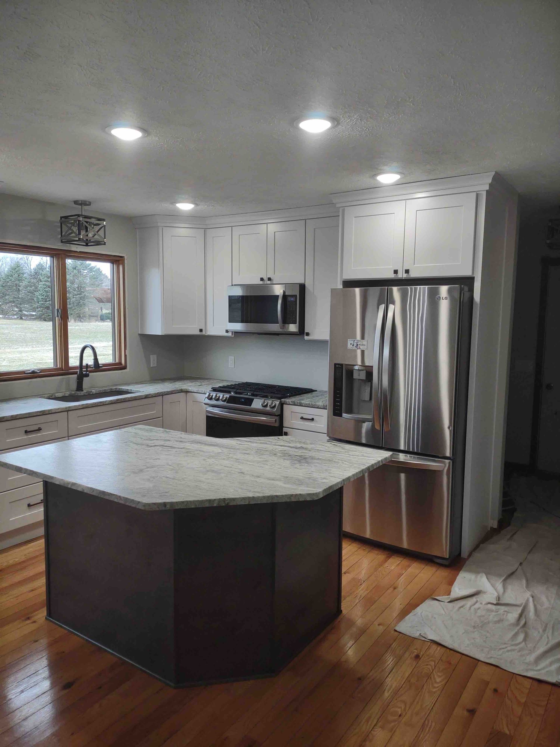 A kitchen with stainless steel appliances and a large island in the middle.