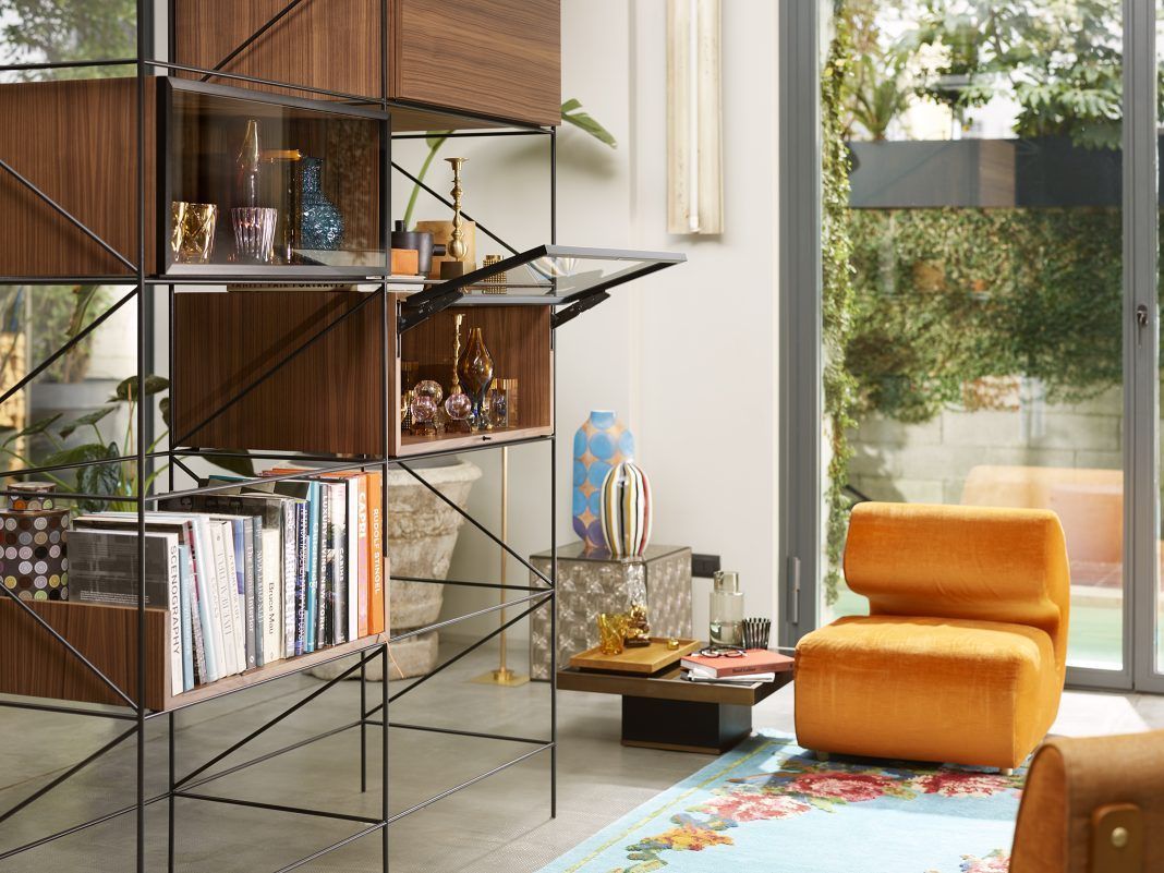 A living room with a bookshelf, chair, table, and sliding glass doors.