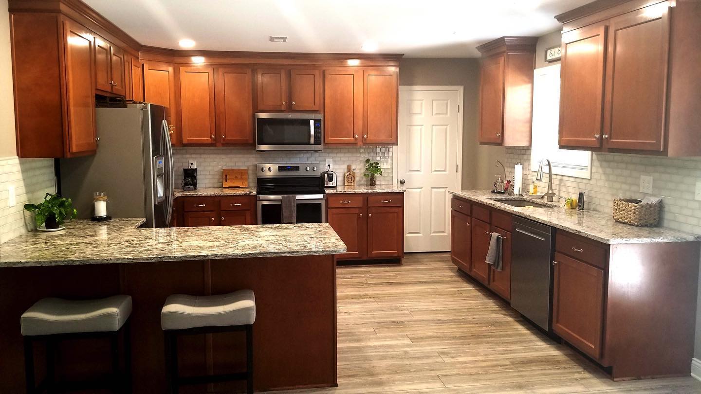 A kitchen with wooden cabinets , granite counter tops , stainless steel appliances , and a large island.