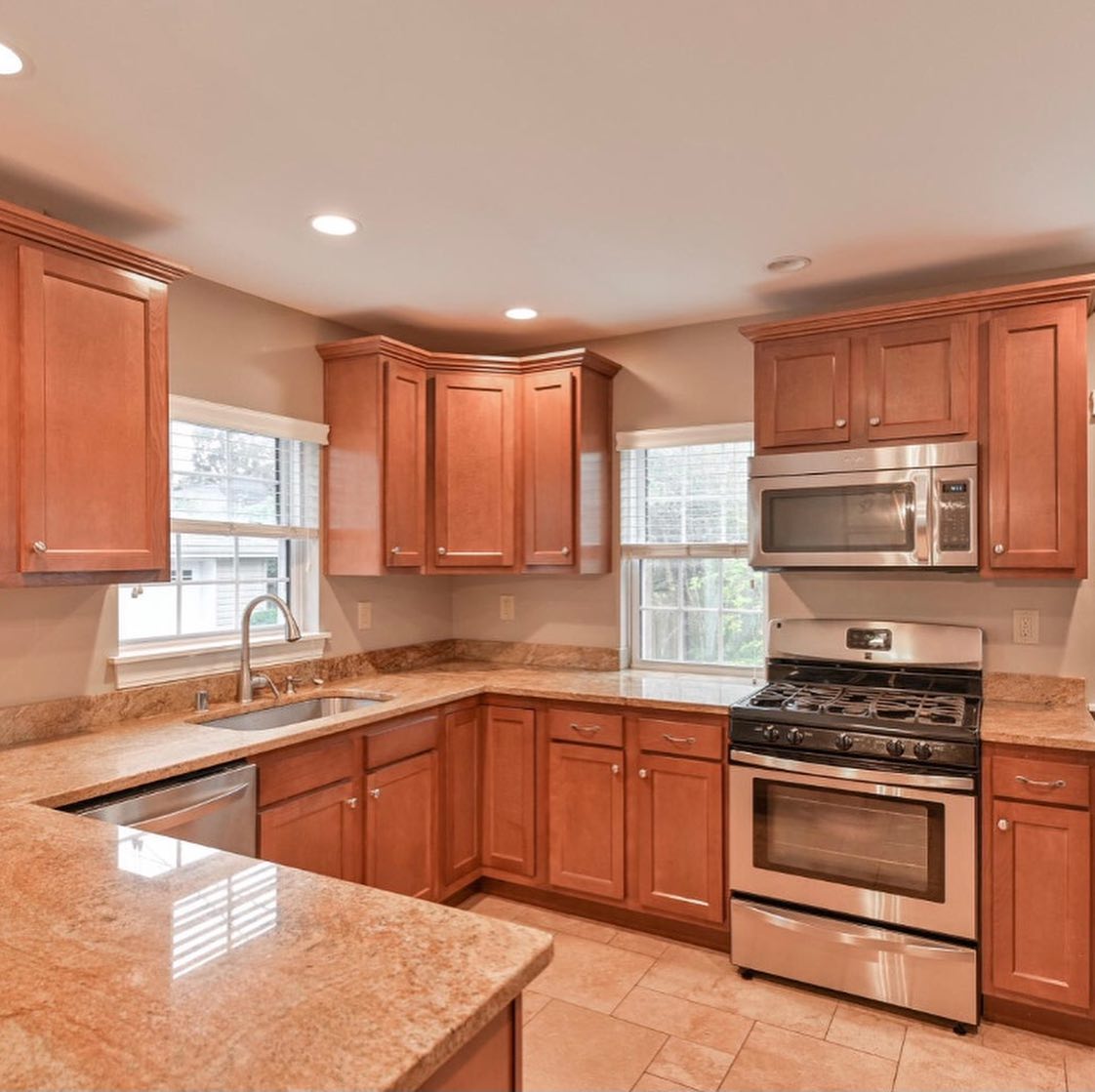 A kitchen with wooden cabinets , granite counter tops , stainless steel appliances and a stove.