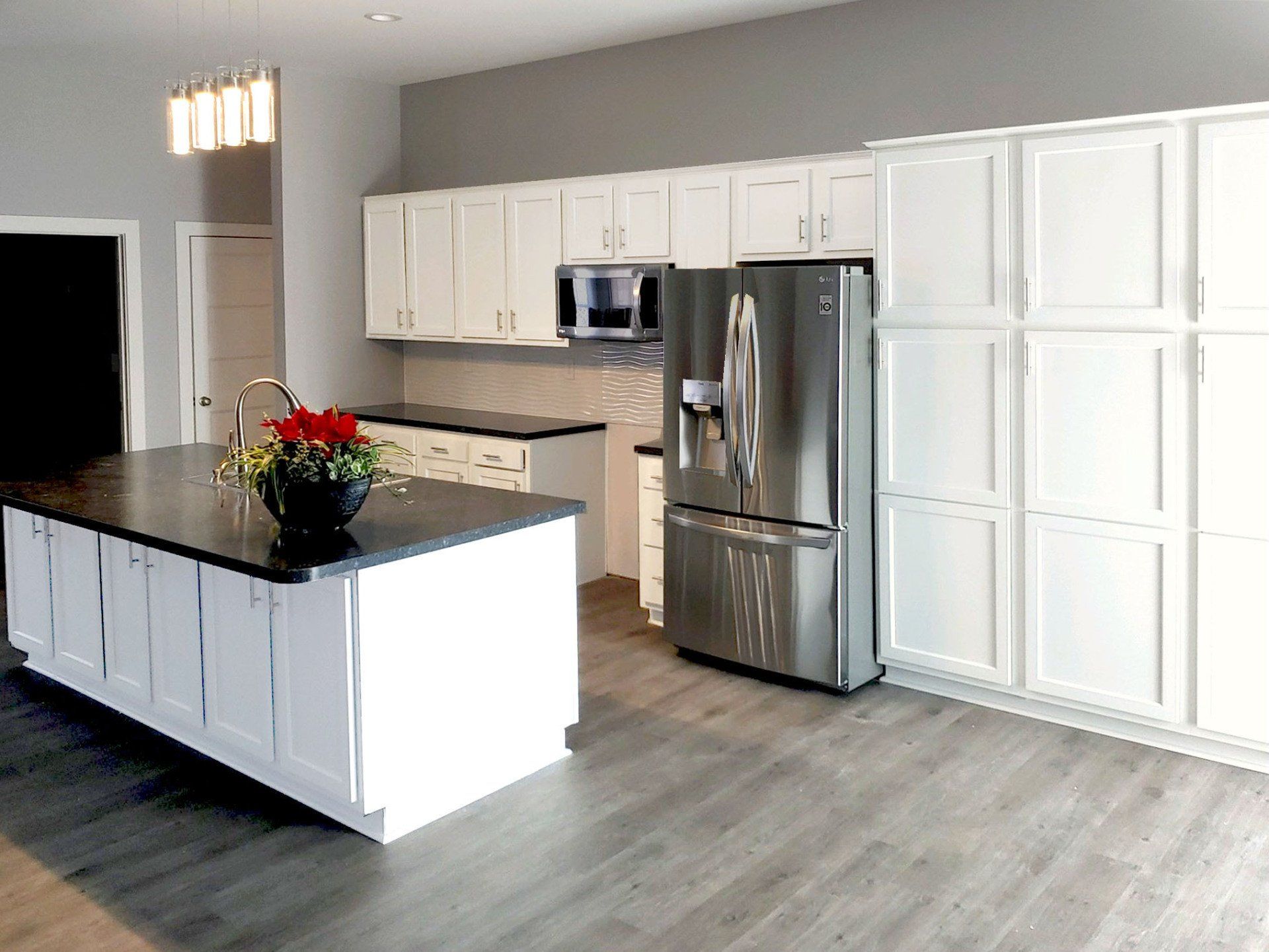 A kitchen with white cabinets , stainless steel appliances , and a large island.