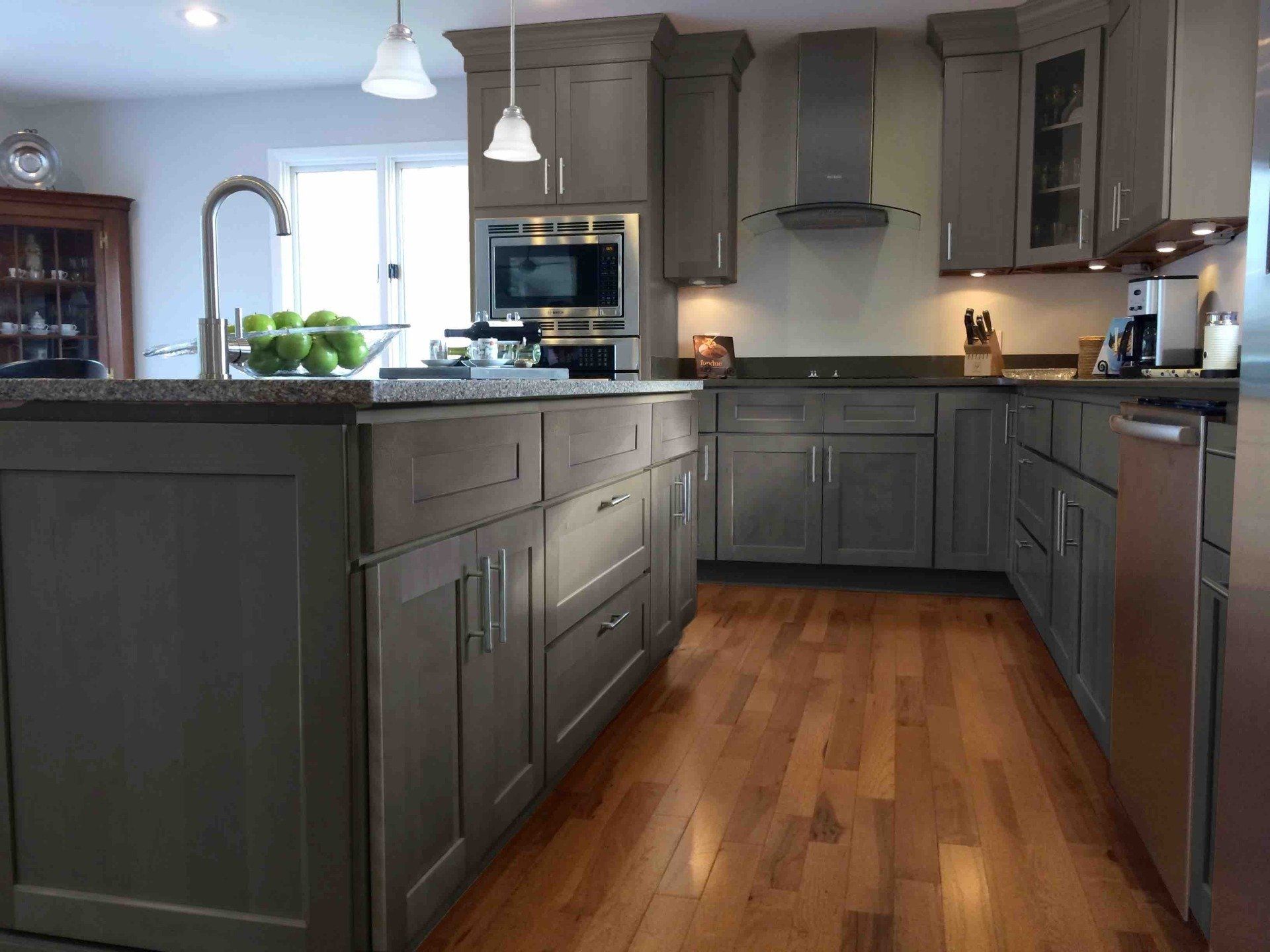 A kitchen with gray cabinets and hardwood floors