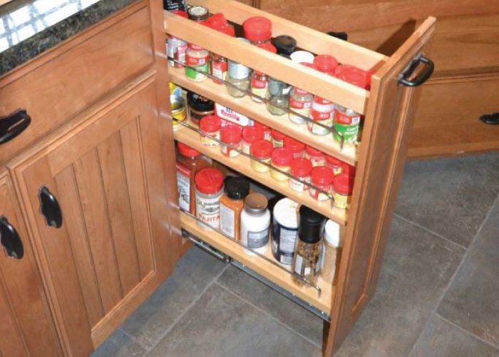 A pull out spice rack in a kitchen filled with spices
