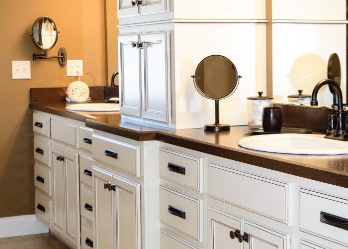 A bathroom with white cabinets , a sink and a mirror.