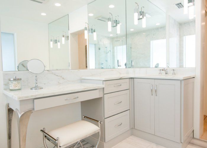 A bathroom with a vanity , sink , mirror and stool.