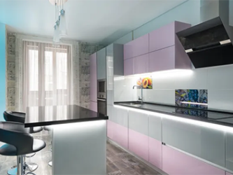 A kitchen with pink and white cabinets and a black counter top.