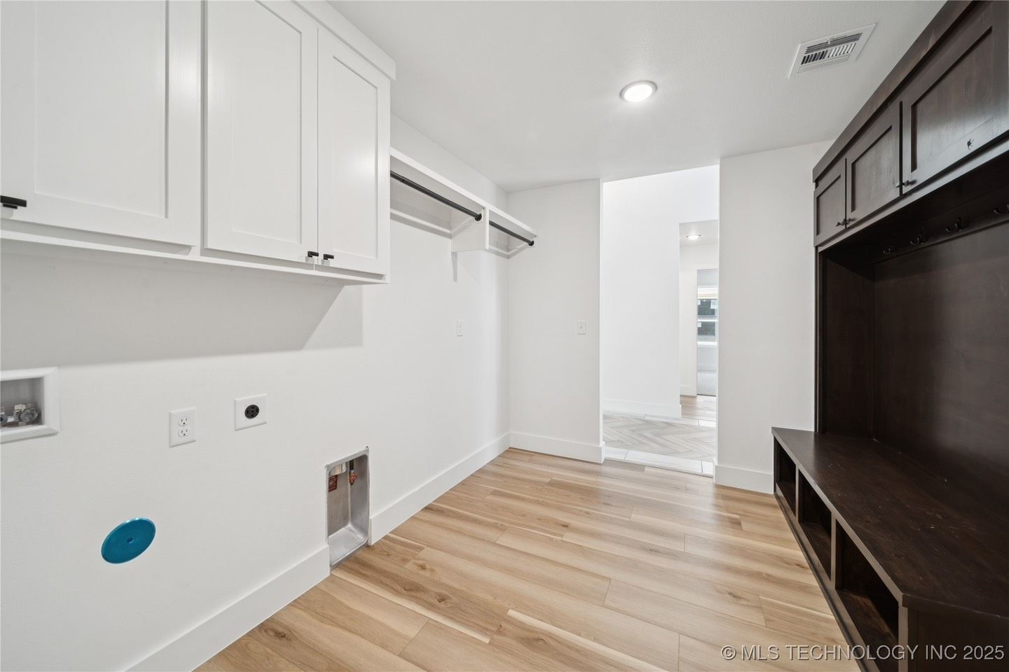 A laundry room with white cabinets and wooden floors.