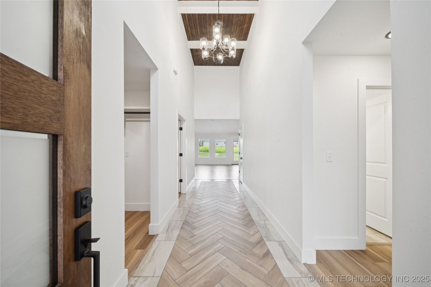 A long hallway with a wooden floor and a chandelier hanging from the ceiling.