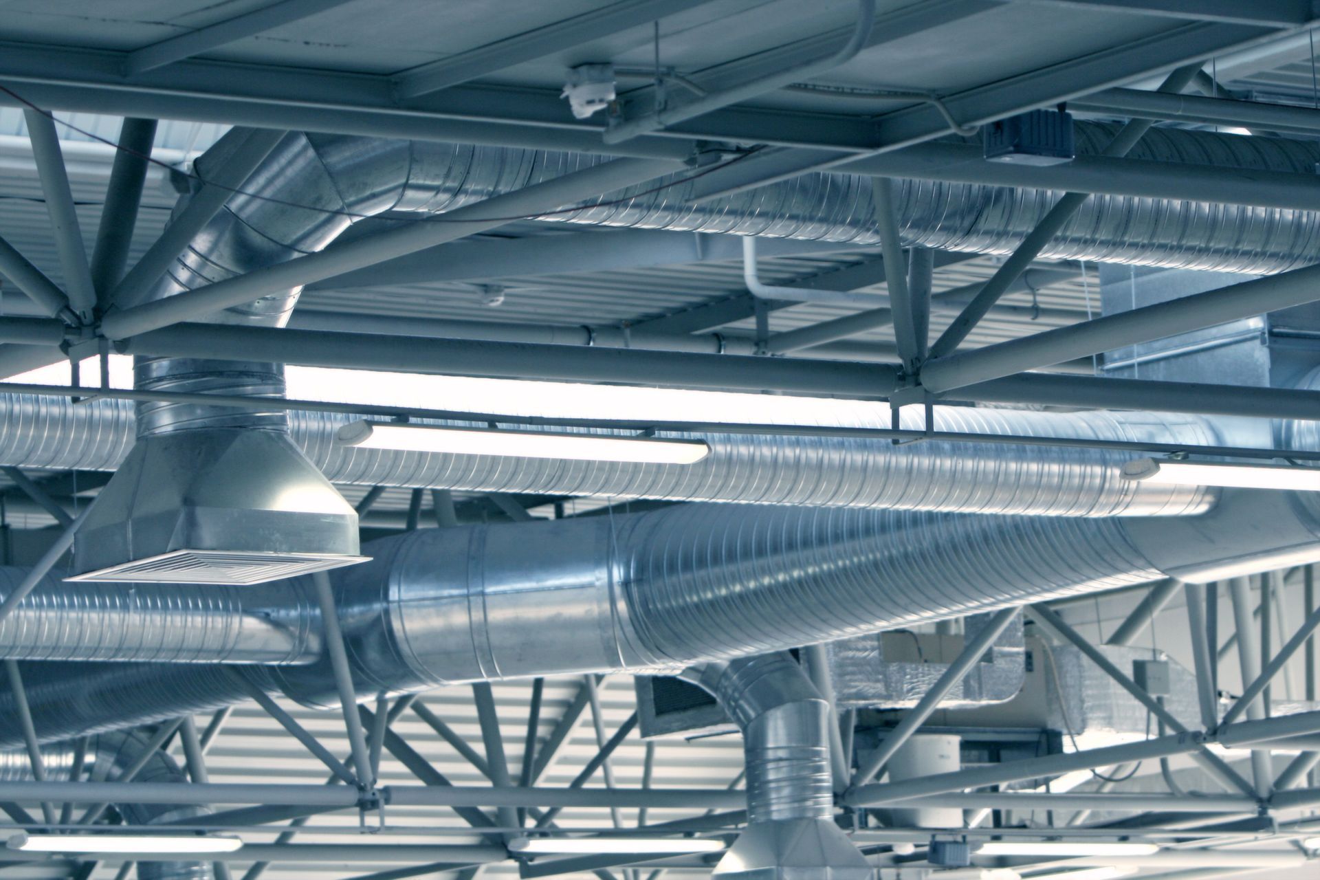 There are a lot of pipes hanging from the ceiling of a building.