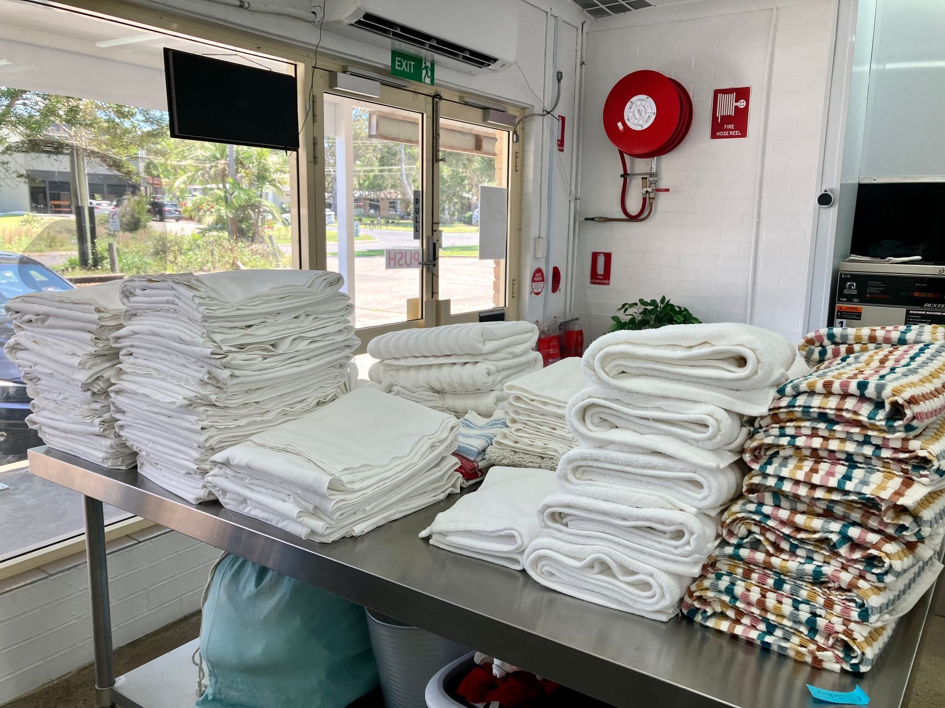 Stacks of Folded White Towels and Patterned Linens — Ezy Laundrette Diamond Beach in Diamond Beach, NSW