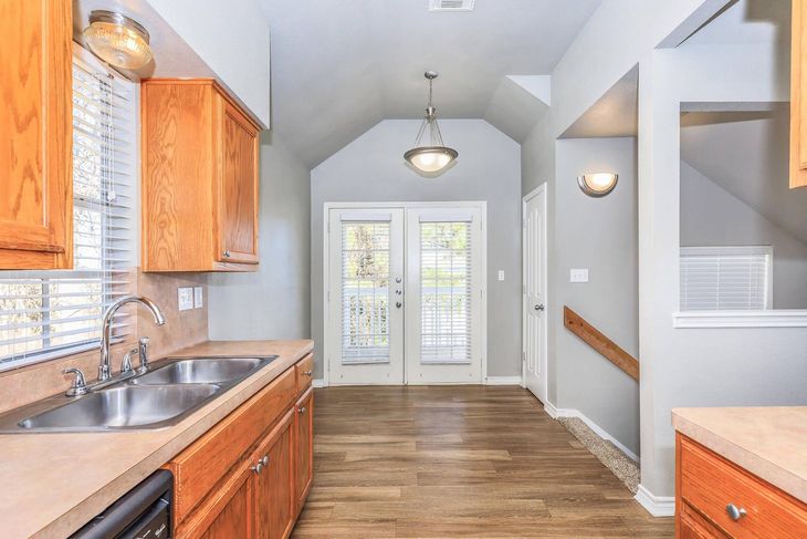 Kitchen with wood cabinets, stainless steel sink, French doors, and a staircase.