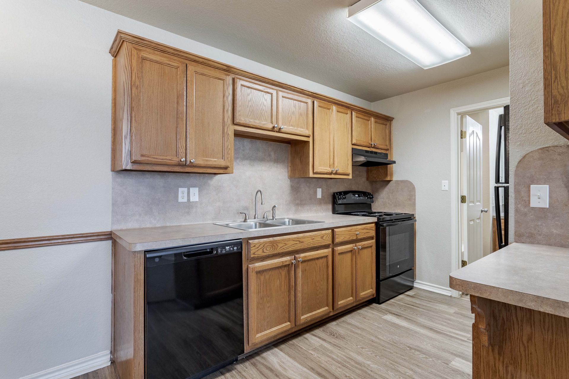Kitchen with wood cabinets, stainless steel sink, French doors, and a staircase.