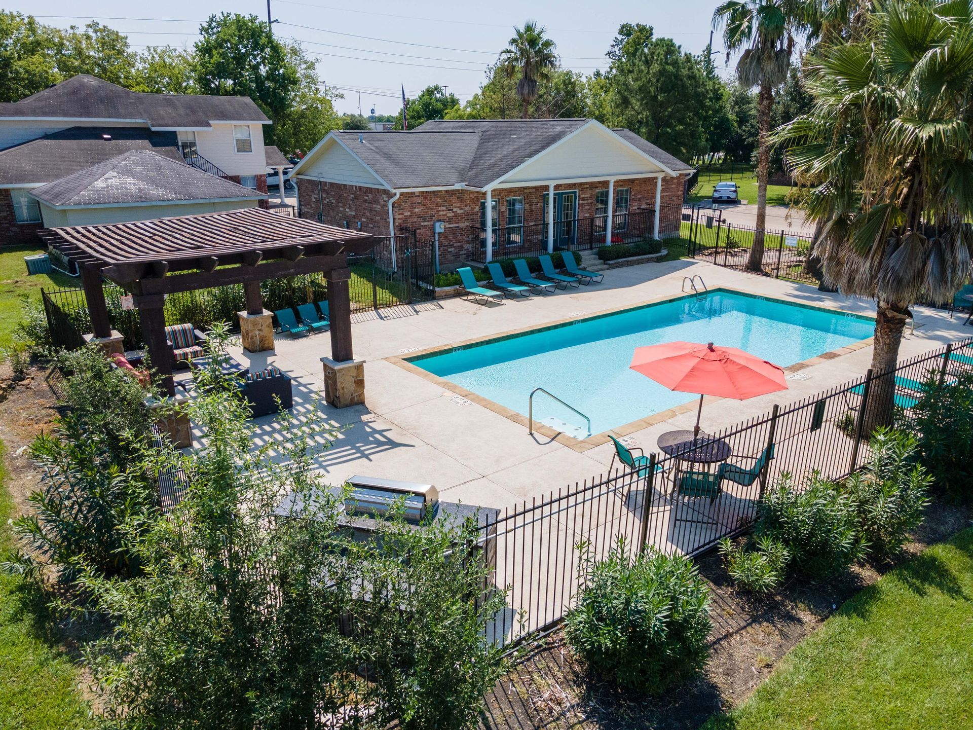 Pool area with brick building, pergola, and lounge chairs.