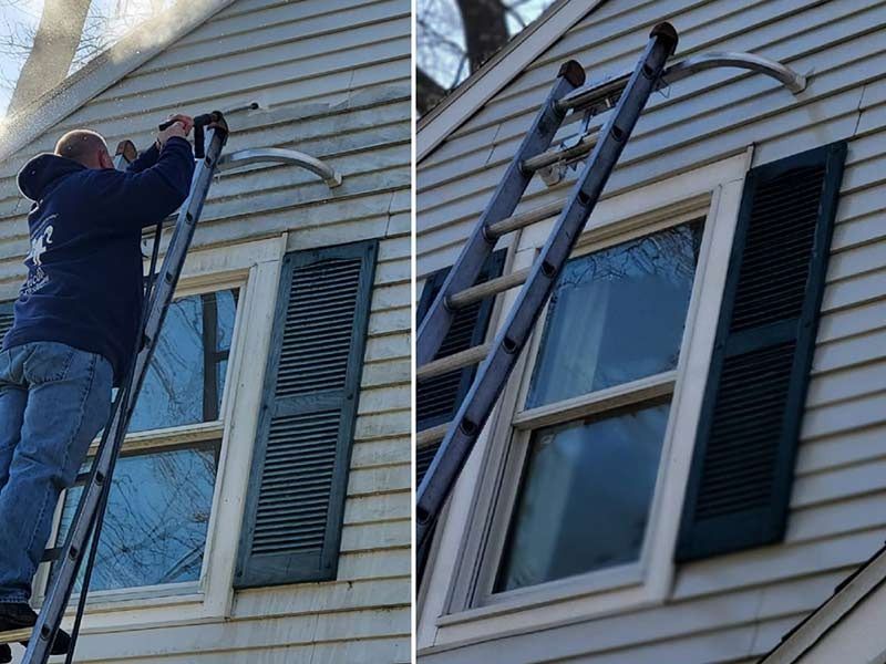 A man is standing on a ladder on the side of a house.
