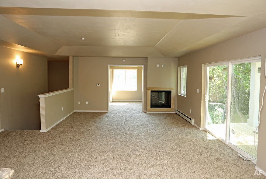 Spacious beige living room with carpet, fireplace, and sliding glass doors to a patio