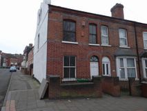 A row of brick houses on a narrow street with cars parked in front of them.