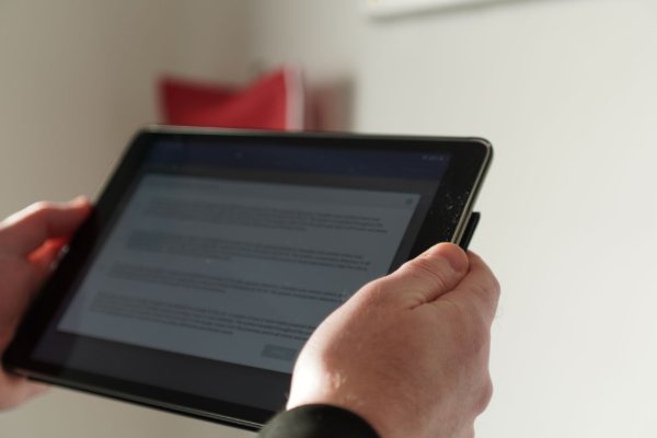Hands holding a tablet displaying text, likely reading.