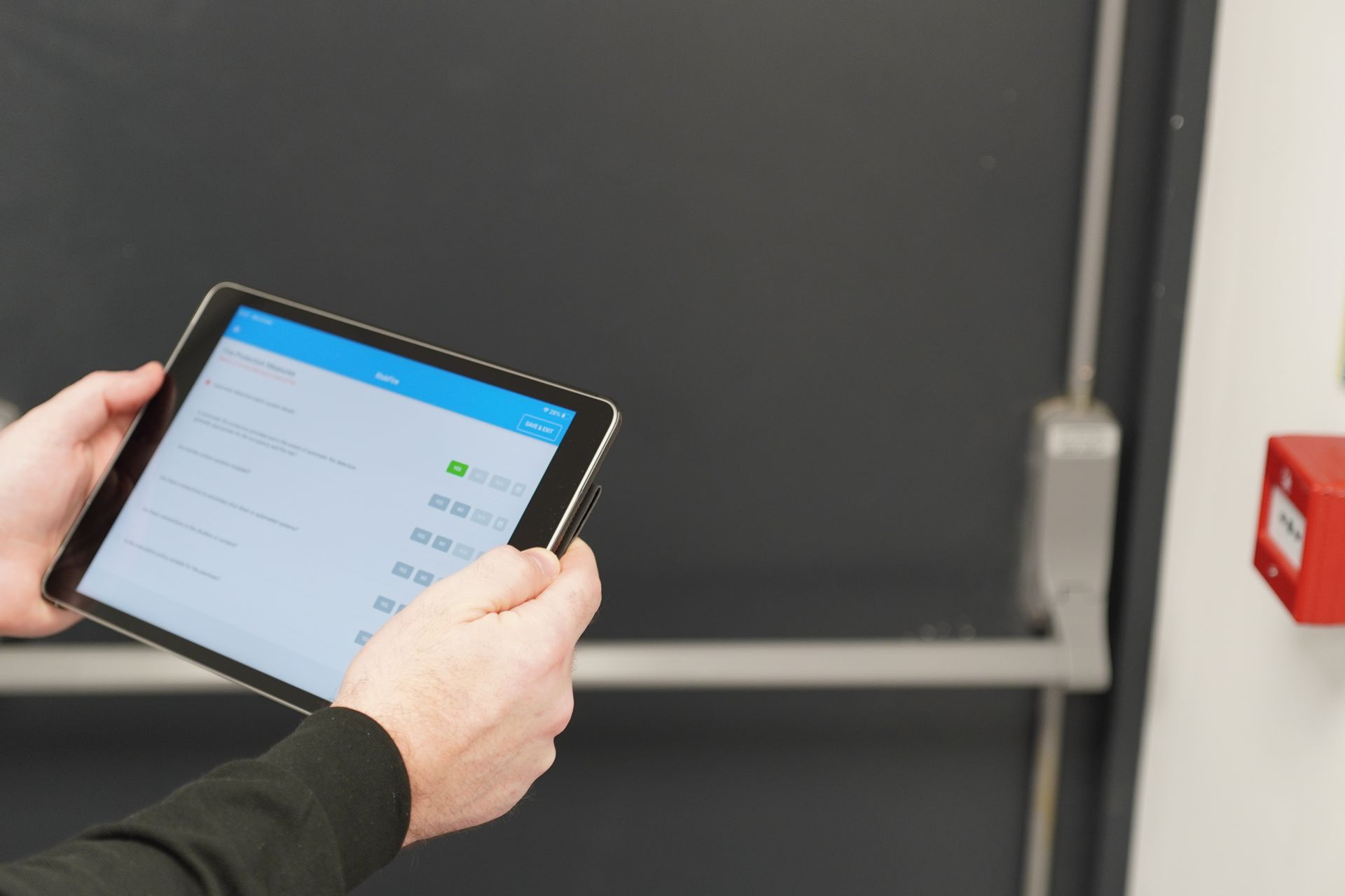 A construction worker is holding a tablet and a pen.