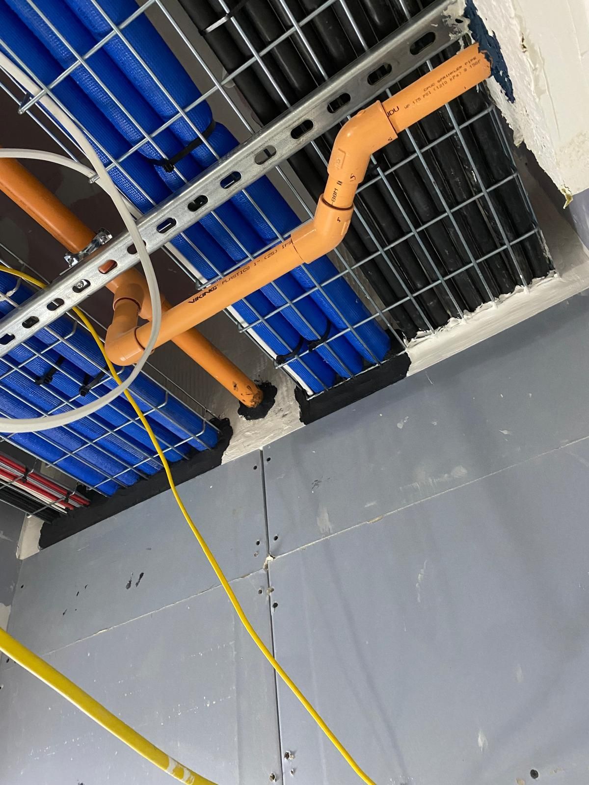 A bunch of pipes are hanging from the ceiling of a building