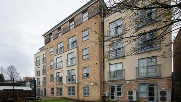 Three-story brick building on a street corner, with storefronts below and 