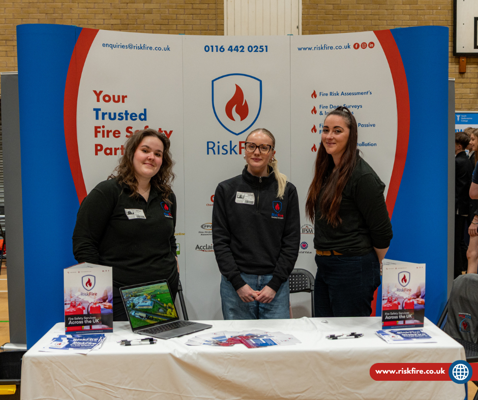Group of people posing outside a red-brick historic building with arches and a clock