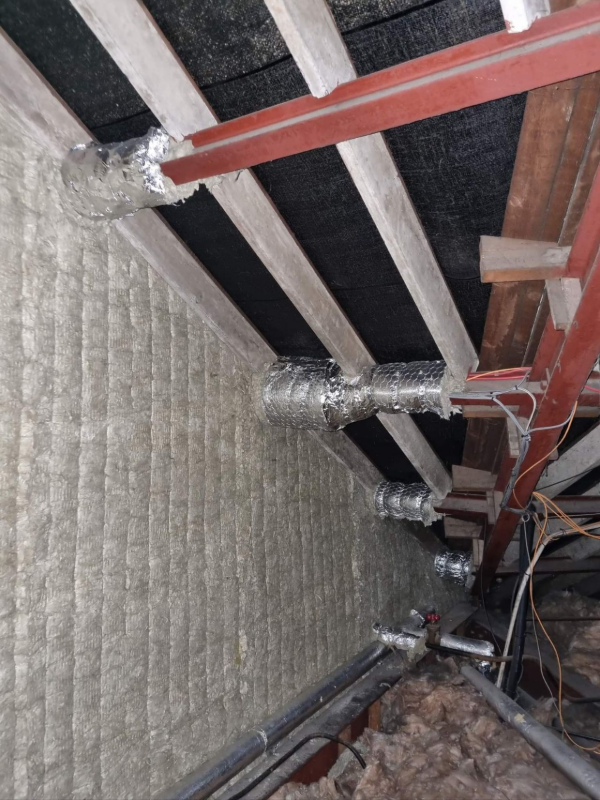 Interior view of attic insulation, ductwork, and wooden beams.