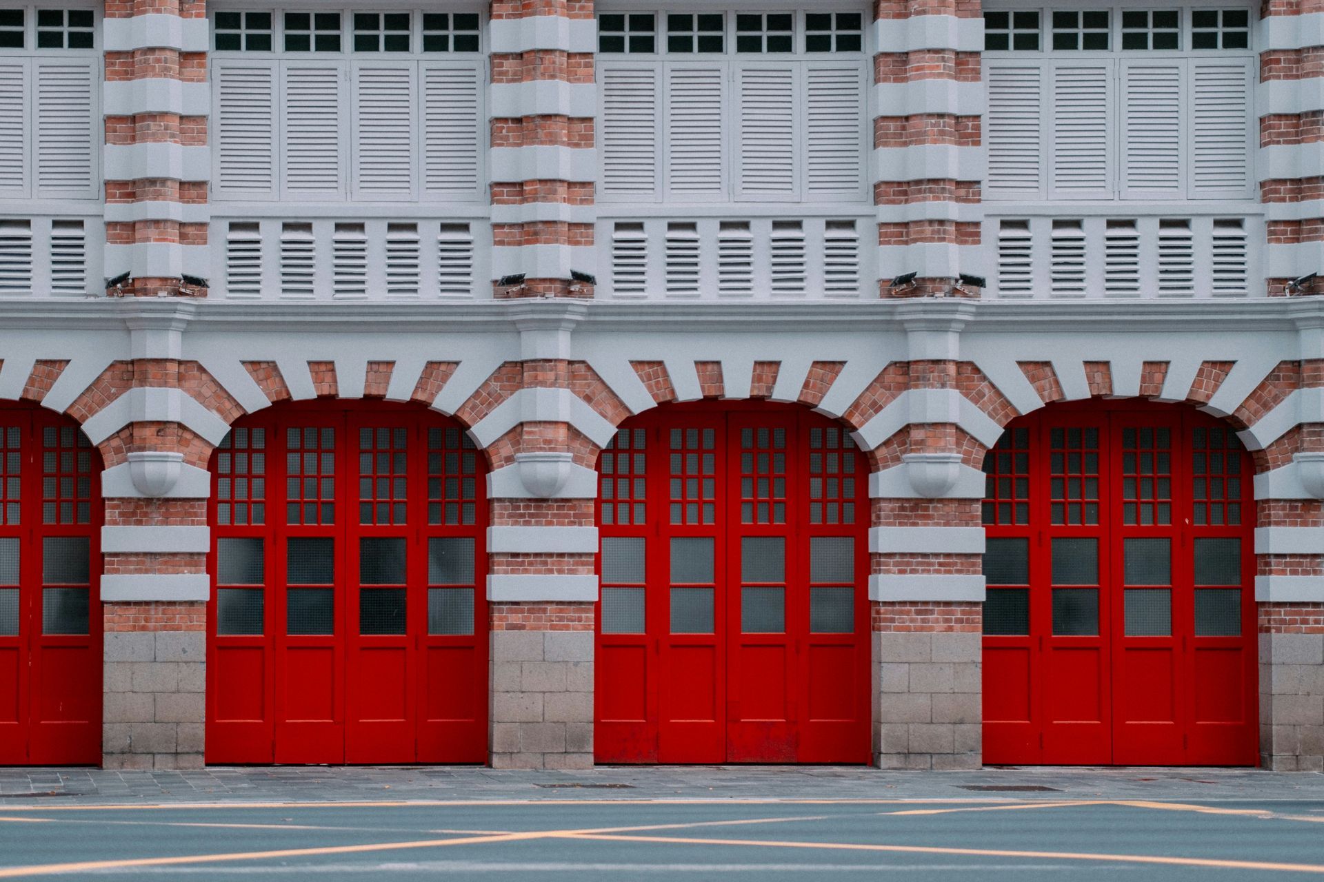 A row of red garage doors on the side of a building.