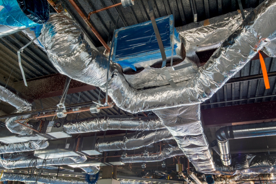 A bunch of pipes are hanging from the ceiling of a building.