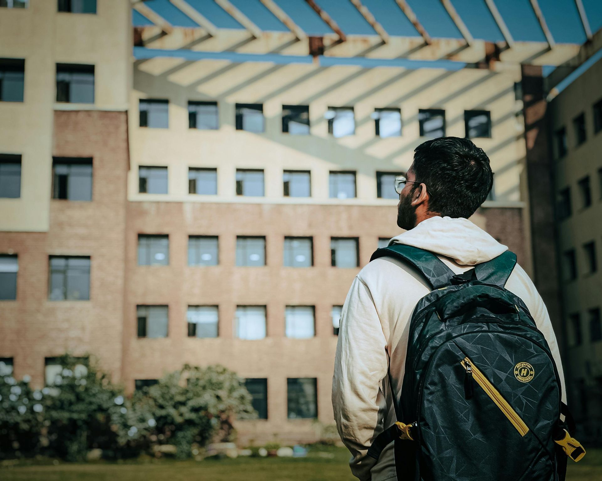 A man with a backpack is standing in front of a building.