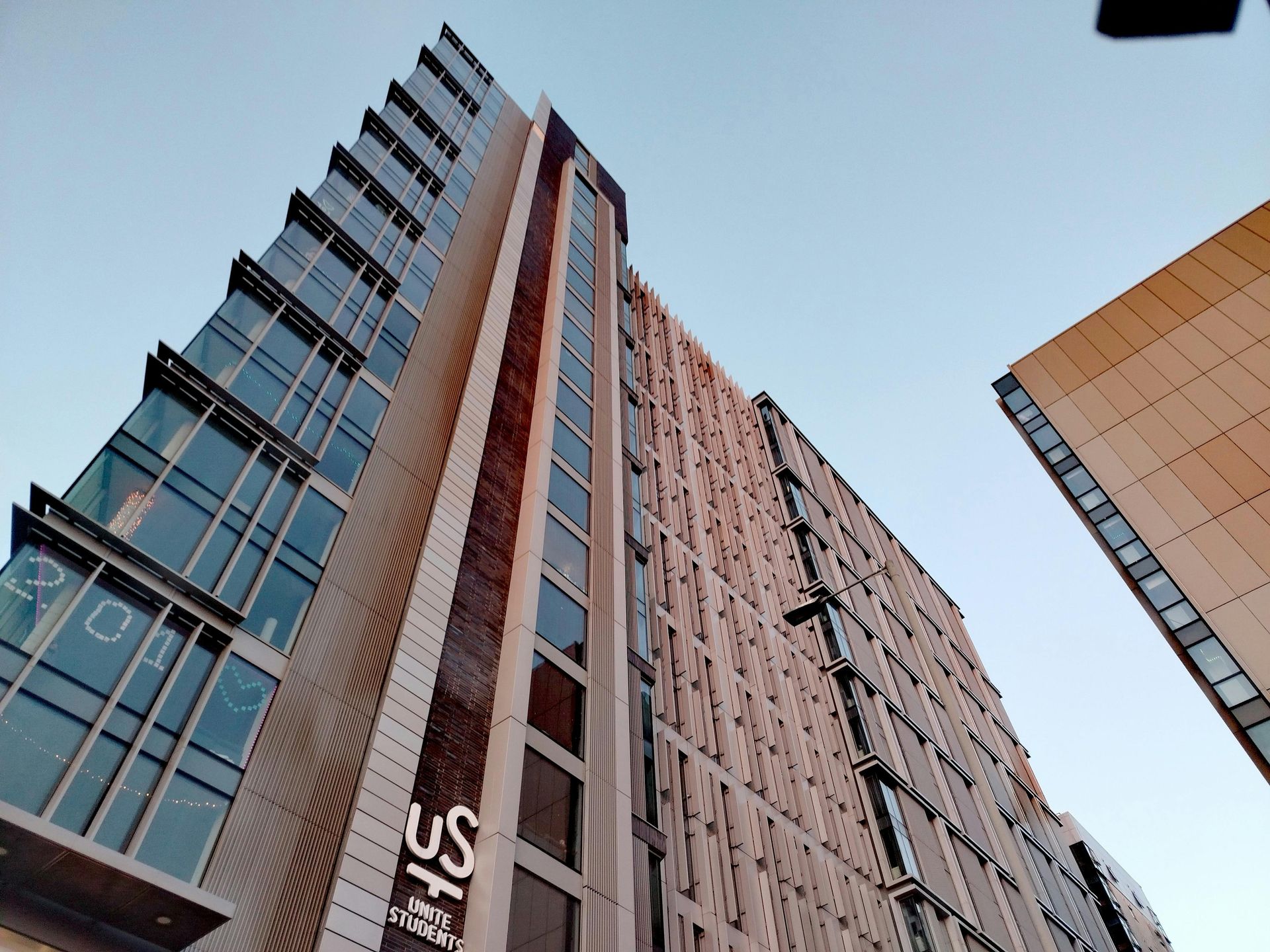 A man in a yellow vest is writing on a clipboard.