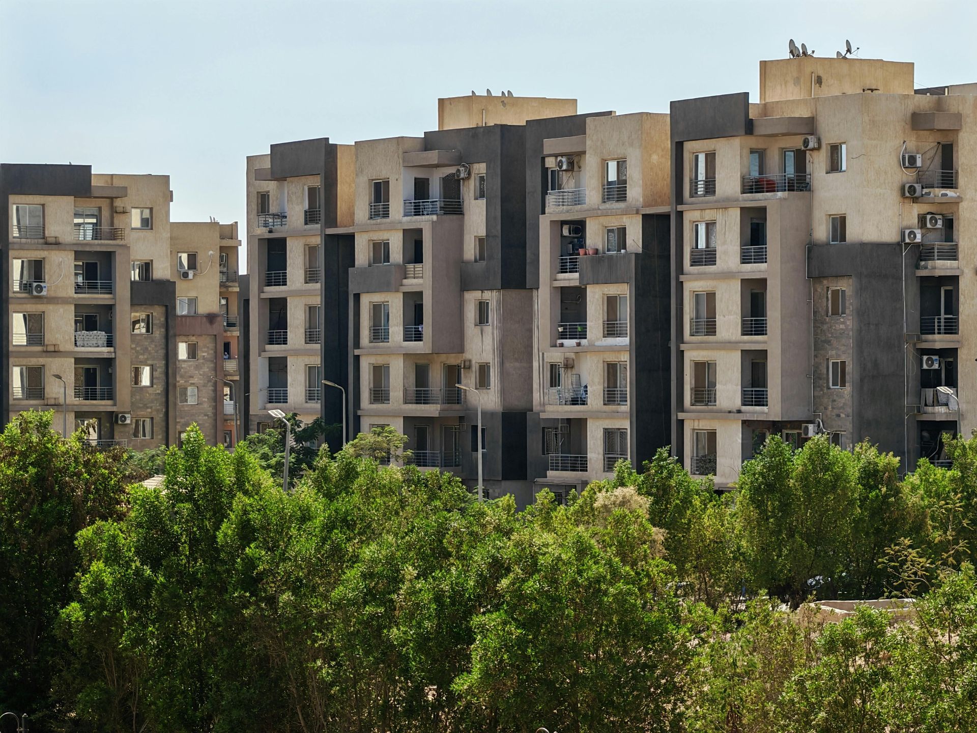 A man in a yellow vest is writing on a clipboard with a pen.