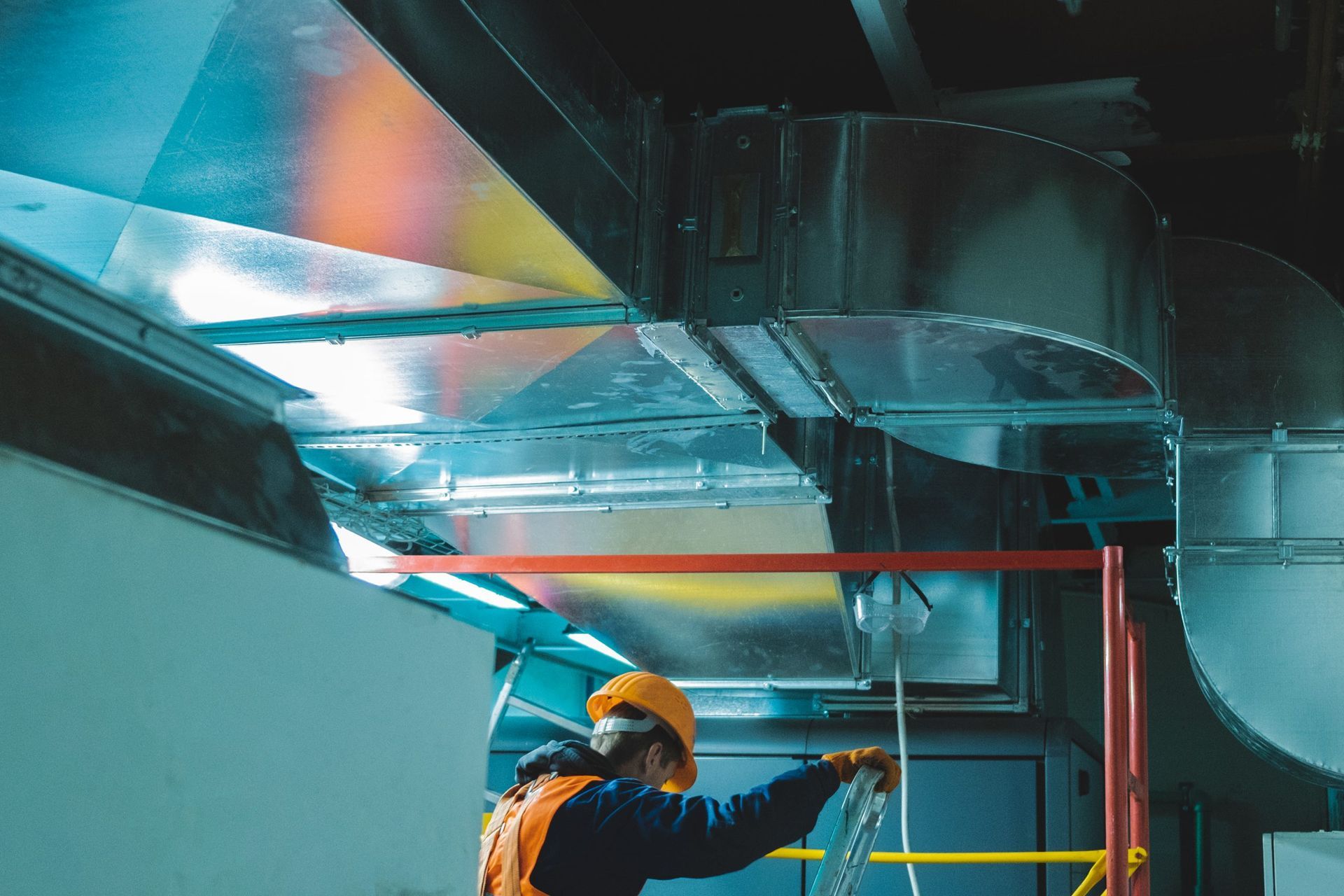 A man is working on a ventilation system in a building.