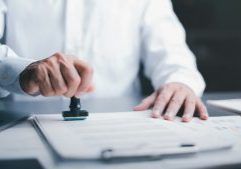 A man is stamping a document on a clipboard.