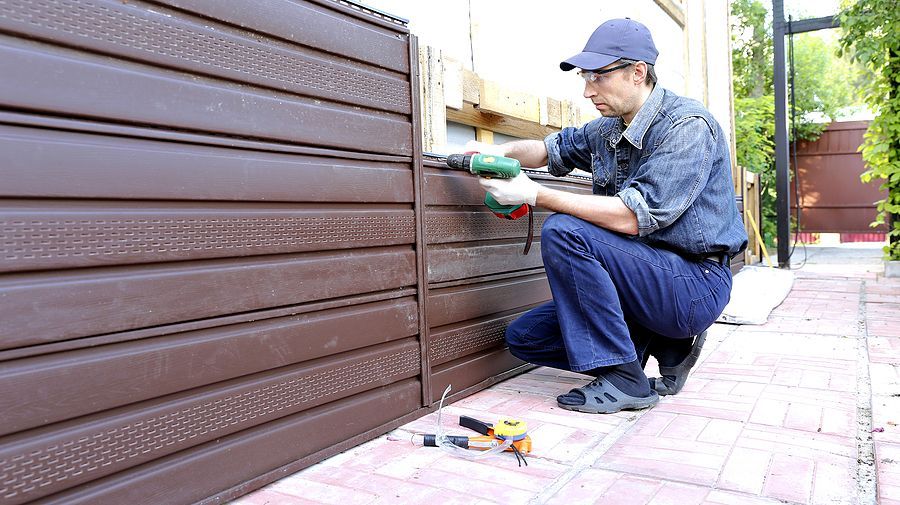 a man in blue overalls working on a garage door