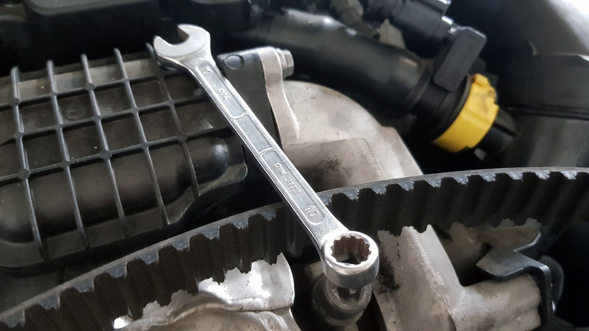 A wrench is sitting on top of a car engine.