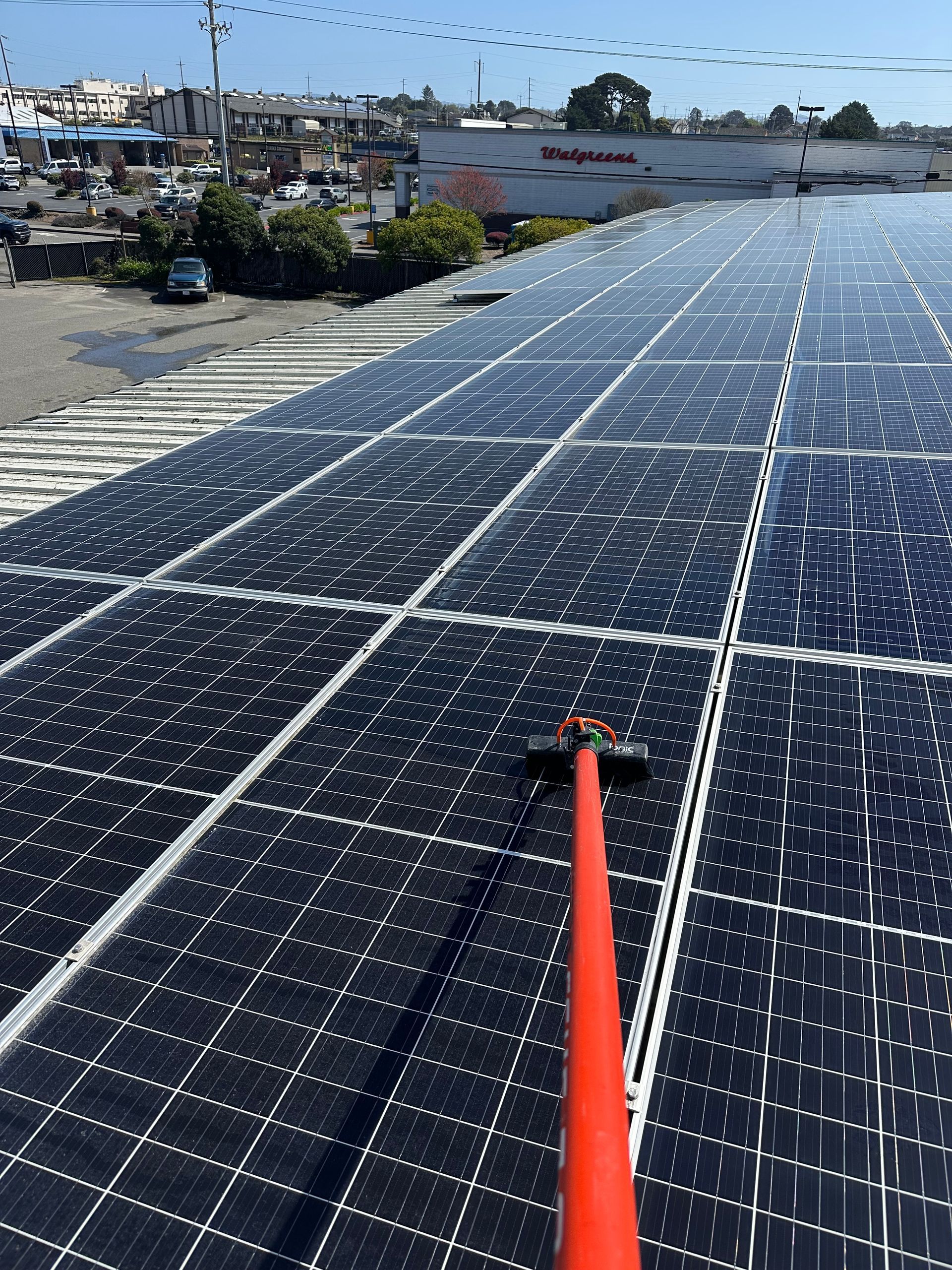 A person is cleaning solar panels on the roof of a building