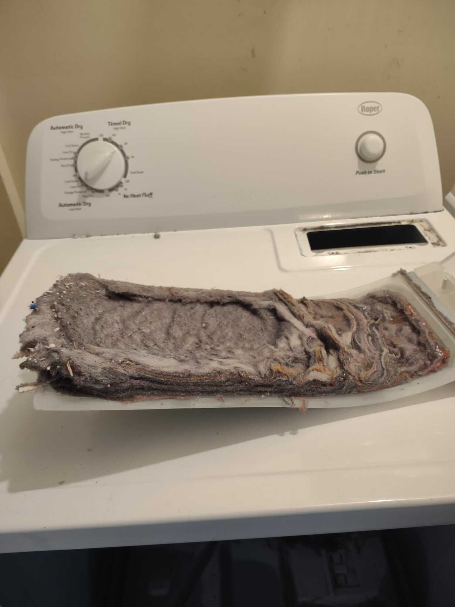 A dirty dryer is sitting on top of a white table.