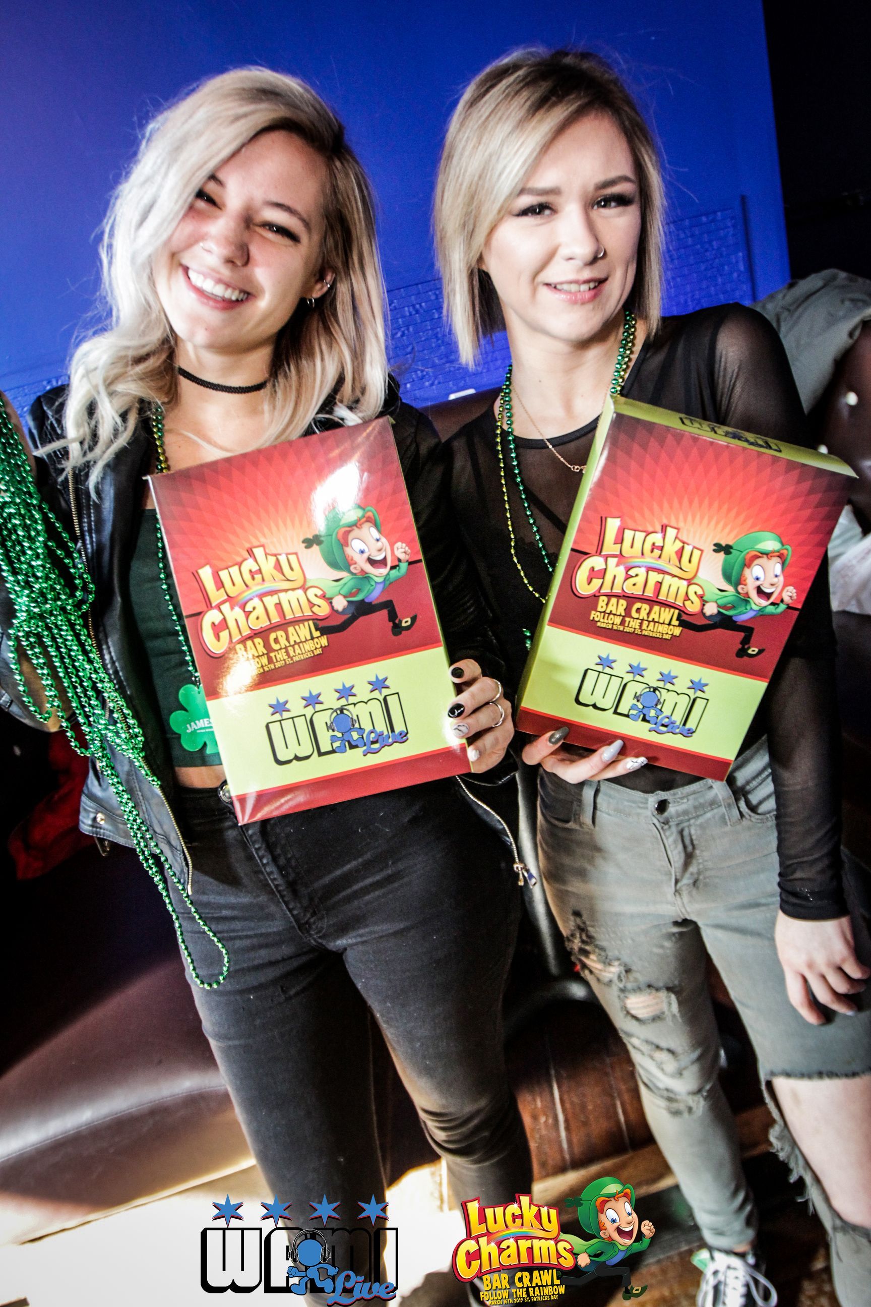 Two women are standing next to each other holding boxes of lucky charms.