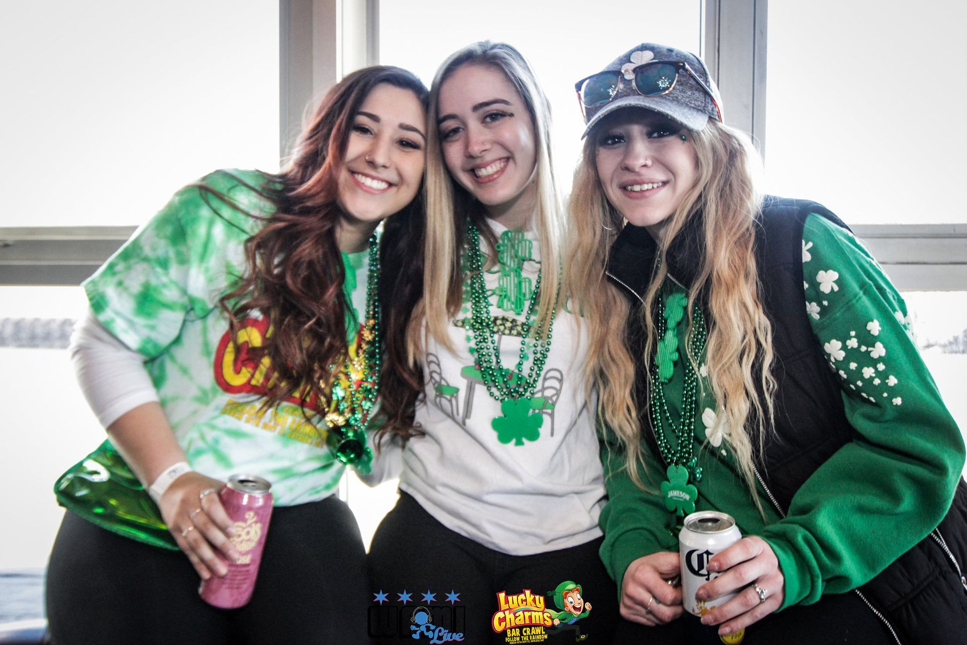 Three women are posing for a picture in front of a window.