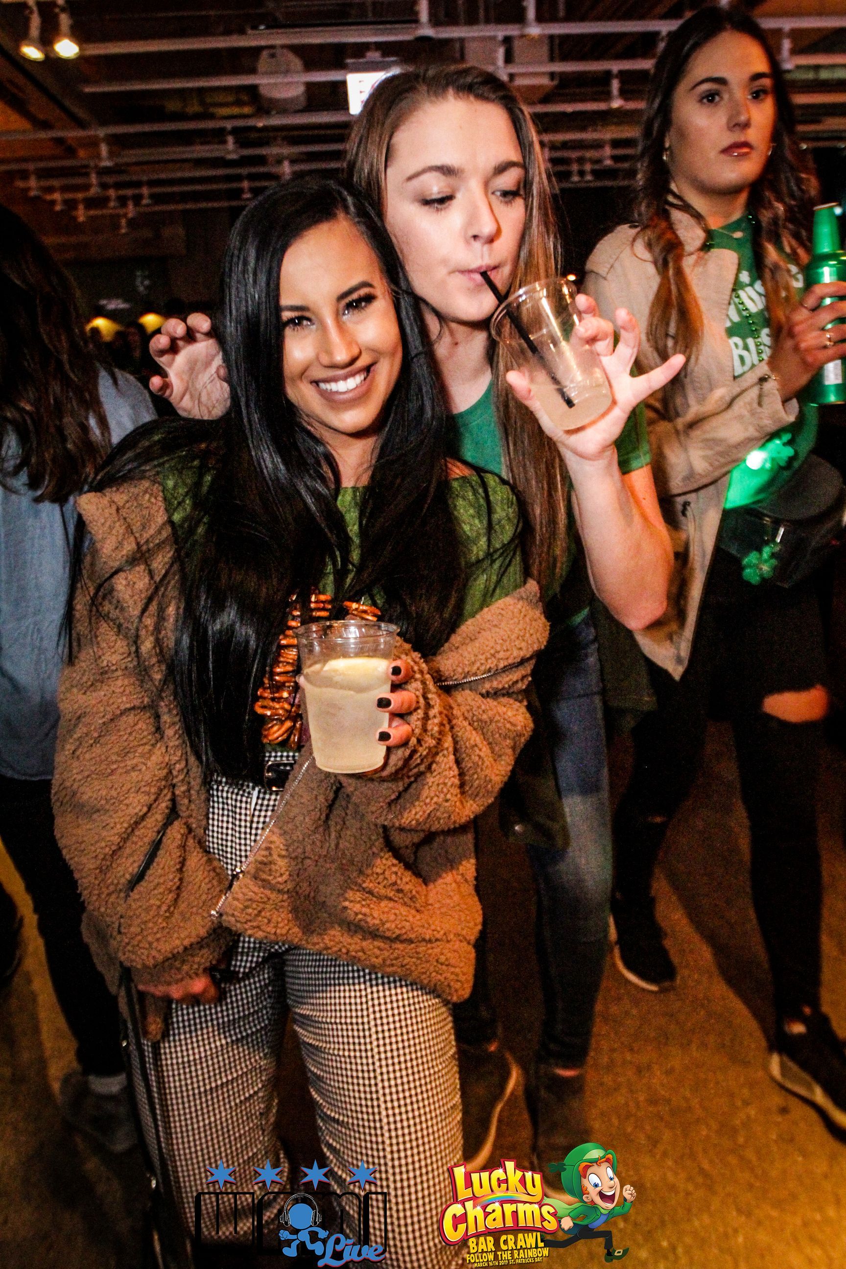 A group of women are standing next to each other holding drinks.