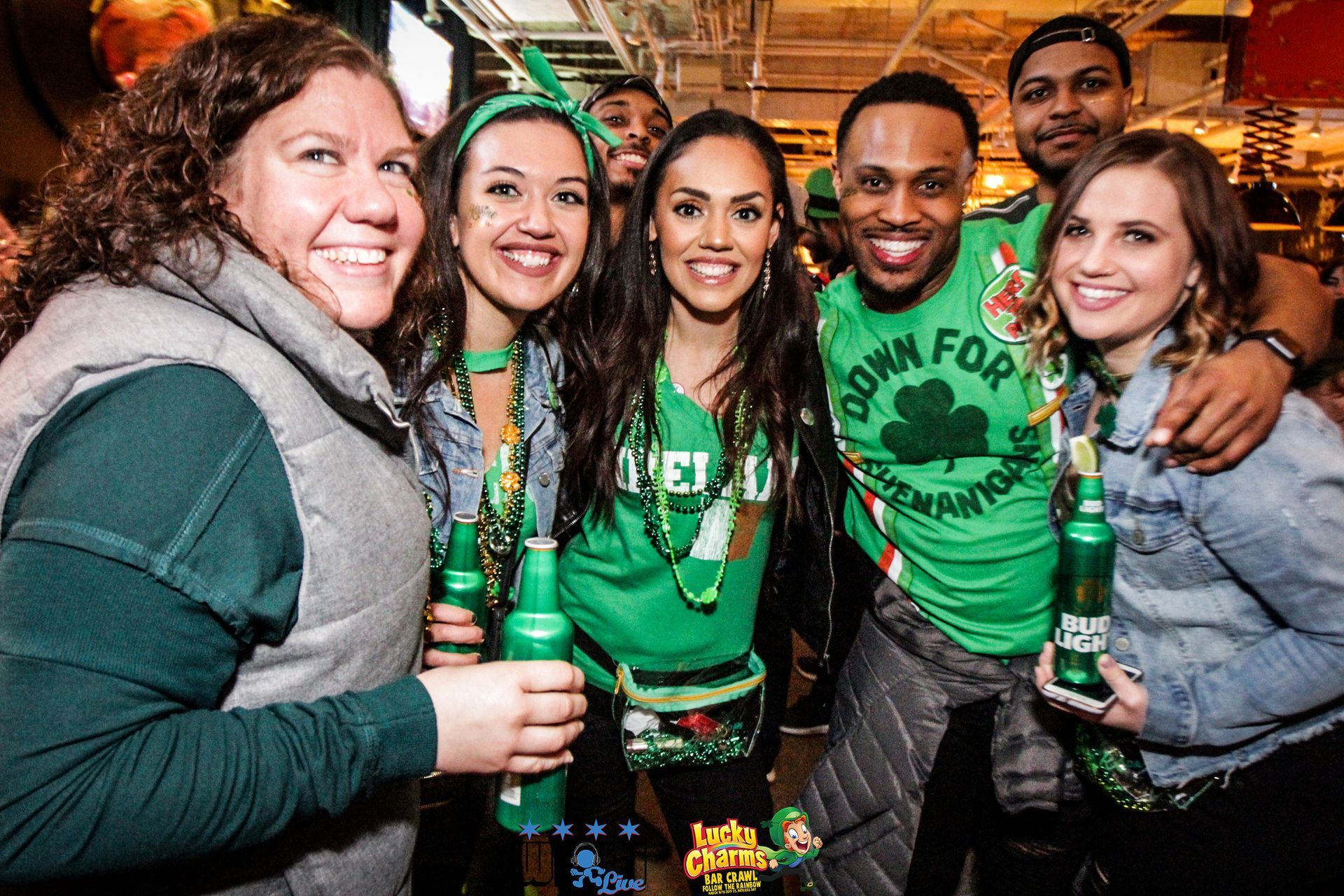 A group of people are posing for a picture while holding beer bottles.