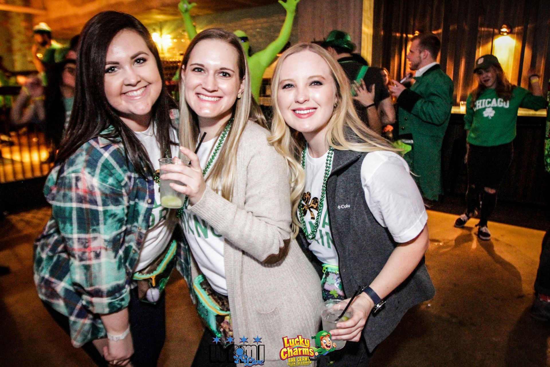 Three women are posing for a picture at a st. patrick 's day party.