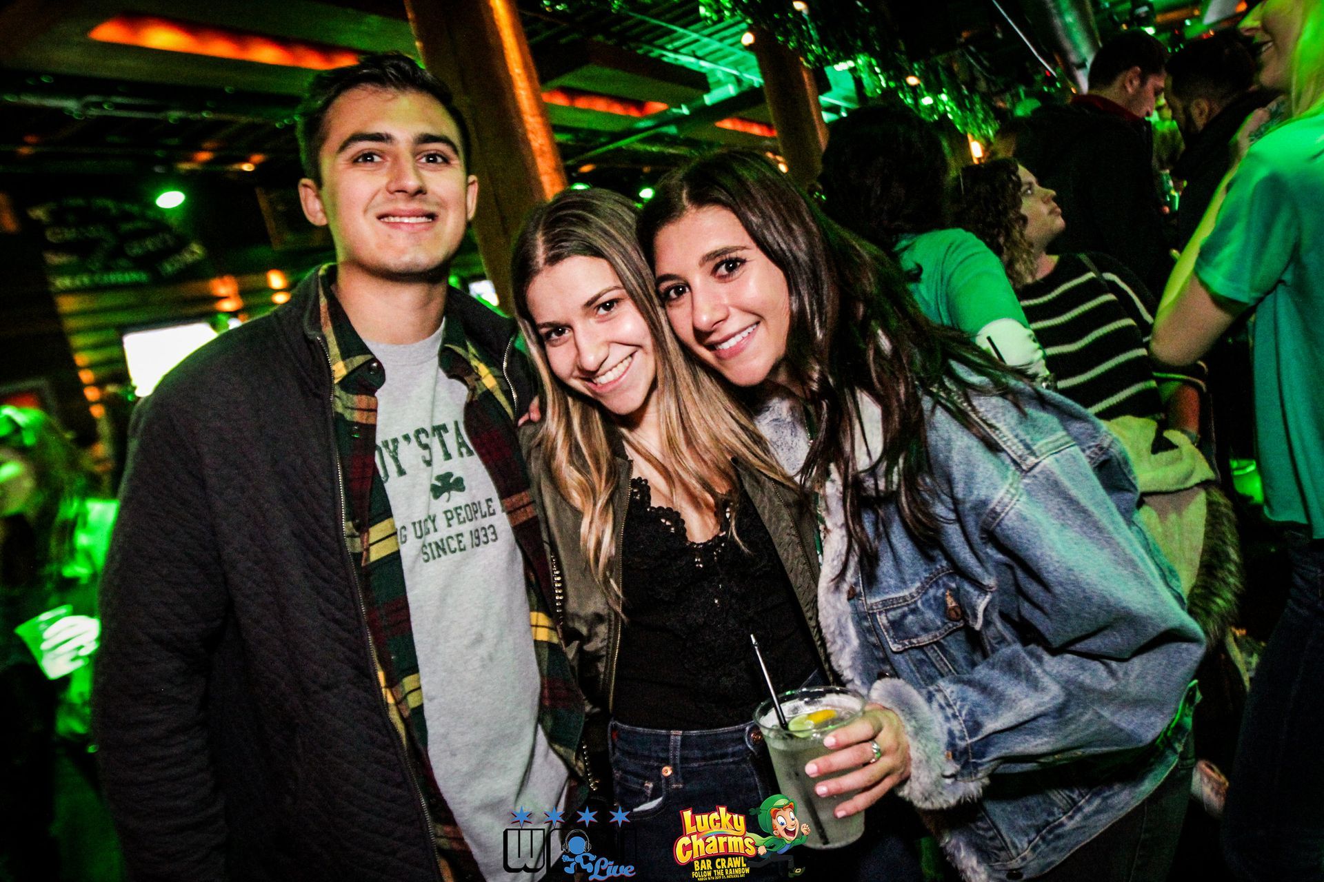 A man and two women are posing for a picture in a club.